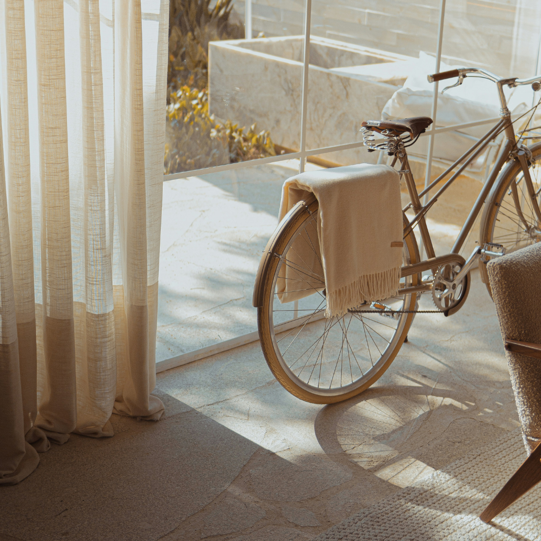 Vintage bicycle with a beige throw in sunlit modern interior, Moodie Saunter Australia gift inspiration