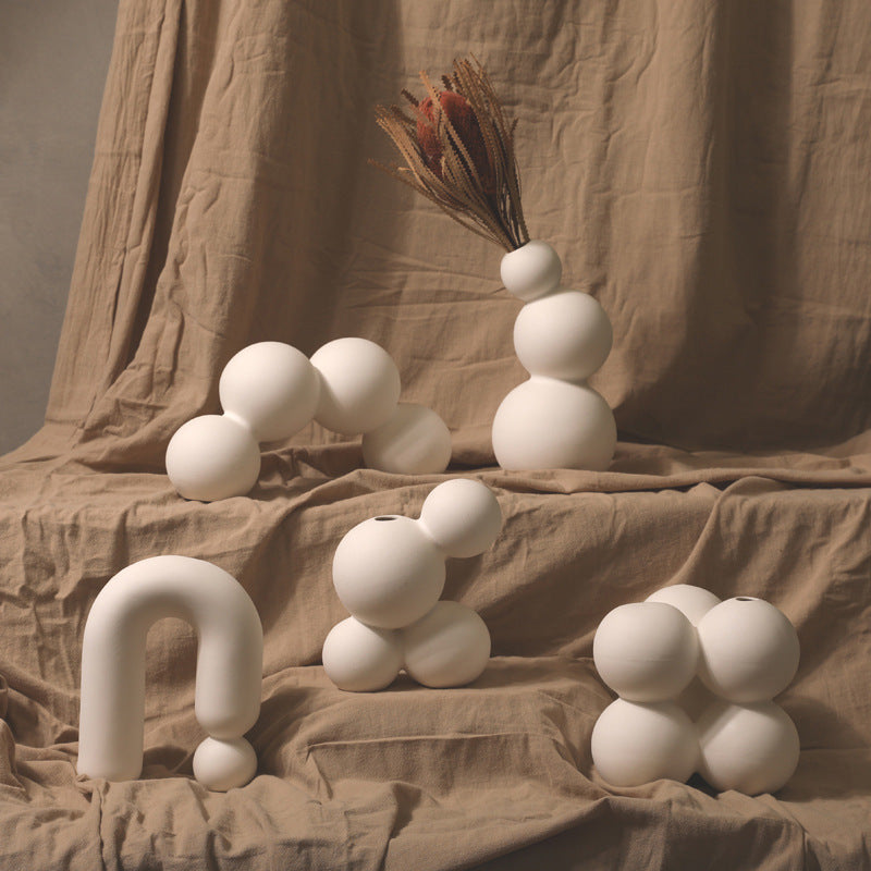 Modern sculptural white ceramic vases with abstract shapes on beige fabric, Moodie Saunter decor
