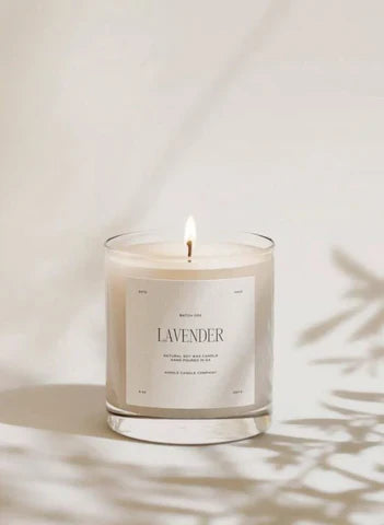 Lit lavender scented candle in a clear glass jar, styled with soft shadows, Moodie Saunter